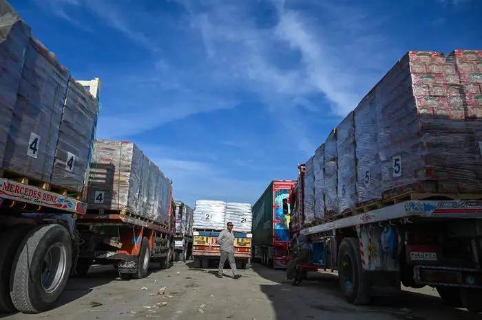 Drivers wait next to their trucks loaded with aid to cross into Gaza from the Egyptian side of the Rafah border crossing in Rafah on January 19, 2025. Trucks carrying humanitarian aid entered the Gaza Strip on January 19 after a long-awaited truce between Israel and Hamas came into effect, the United Nations said. (Photo by Khaled DESOUKI / AFP)