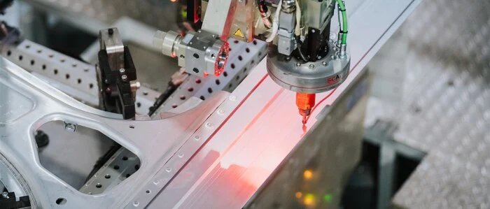 Automatisierte Präzisionsarbeit: Ein Roboter trägt Klebstoff an einer Fahrzeugkarosserie auf | Automatisierte Präzisionsarbeit: Ein Roboter trägt Klebstoff an einer Fahrzeugkarosserie auf