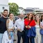Mehrere Personen stehen auf einem gut besuchten Platz und lachen in die Kamera