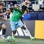 Vancouver Whitecaps FC defender Tate Johnson and Seattle Sounders FC forward Georgi Minoungou battle for the ball during the second half of an MLS soccer match Saturday, Sept. 27, 2025, in Seattle. (AP Photo/Kevin Ng)
