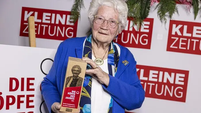 Zu sehen ist eine Dame mit weißen Haaren und einem dunkelblauen Blazer 