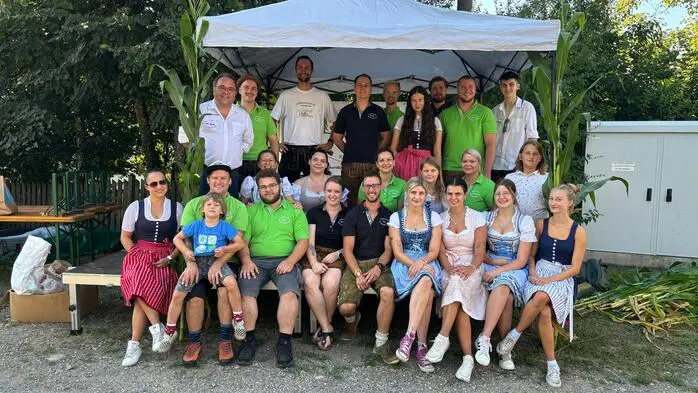 Mehrere Frauen, Männer und Kinder stehen unter einem Partyzelt und lächeln in die Kamera