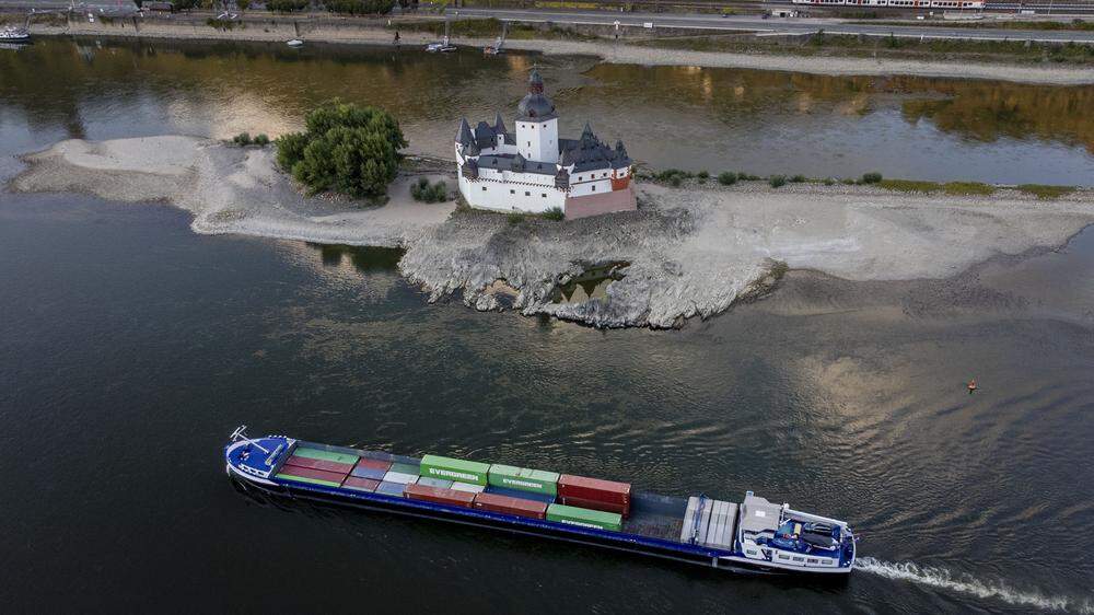 Auf vielen Flüssen wie dem Rhein sind die Pegelstände so niedrig, dass Schiffe nur noch mit einem Bruchteil des Üblichen beladen werden können. Im Bild: ein Containerschiff passiert die Burg Pfalzgrafenstein in Kaub 