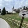 Ein „Betreten verboten“-Schild ist im Vordergrund zu sehen, es wurde in das Bild hineinmontiert. Im Hintergrund ist eine Kirche zu sehen.