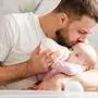 Young father kiss baby during drinking milk. Nursing a baby. Feeding newborn with formula in a bottle.
