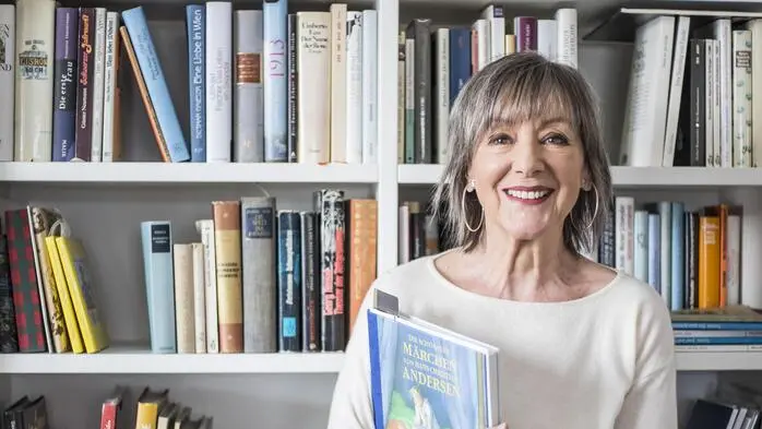 Eine ältere Frau steht vor einem Bücherregal