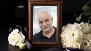 Ein Bild von einem Mann in einem Bilderrahmen, daneben liegen weiße Blumen