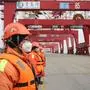 This photo taken on February 4, 2020 shows Chinese employees wearing protective facemasks working at a port in Qingdao in China's eastern Shandong province. - More Chinese cities hunkered down by fencing off streets and telling millions of people to stay home as the death toll from the new coronavirus soared to nearly 500 on February 5. (Photo by STR / AFP) / China OUT