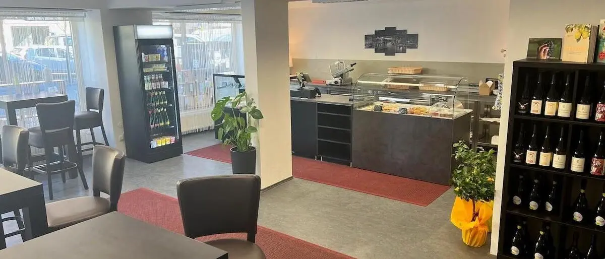 Eine Theke mit Feinkost und mehrere Tische mit Stühlen