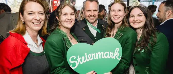 Vier Frauen und ein Mann lachen in die Kamera, der Mann hält ein grünes Herz in seinen Händen.