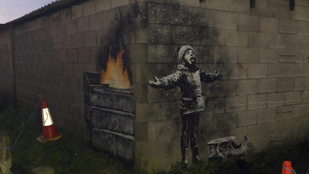 Streetart-Künstler Banksy hat mit einem winterlichen Graffiti eine nachdenkliche Weihnachtsbotschaft an einer Garagenwand in Wales hinterlassen