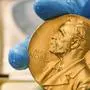 FILE- In this file photo dated Friday, April 17, 2015, a national library employee shows the gold Nobel Prize medal awarded to the late novelist Gabriel Garcia Marquez, in Bogota, Colombia. The Nobel prize has greater personal impact than merely receiving the monetary award, as it marks the recipient in terms of esteem and global recognition. (AP Photo/Fernando Vergara, FILE)