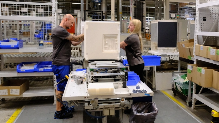 Eine Mitarbeiter und ein Mitarbeiter von Liebherr bei der Montage eines Kühlschranks