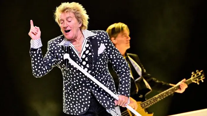 Sänger Rod Stewart mit Mikrofon und E-Gitarrist auf der Bühne