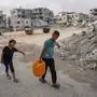 Palestinian children carry back water containers refilled from a nearby supply point in Khan Yunis in the southern Gaza Strip on July 22, 2024, amid the ongoing conflict between Israel and the Palestinian Hamas militant group. (Photo by Bashar TALEB / AFP)
