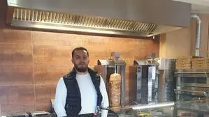 Ein Mann mit Bart steht hinter einer Vitrine in einem Kebab-Laden