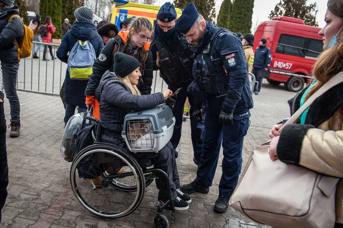 Eine Frau im Rollstuhl spricht mit polnischen Polizisten in Hala Kijowksa, einem zum Flüchtlingslager provisorisch umgebauten Einkaufszentrum in unmittelbarer Grenznähe. 