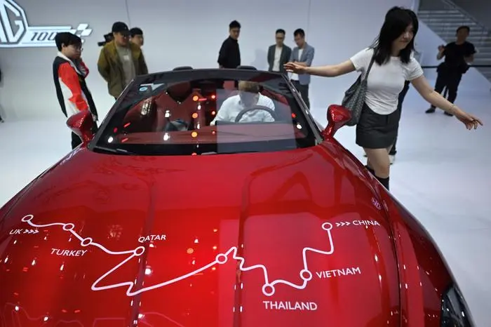 Visitors look at a MG Cyberster electric sports car displayed at the Beijing Auto Show on April 25, 2024. (Photo by Pedro PARDO / AFP)