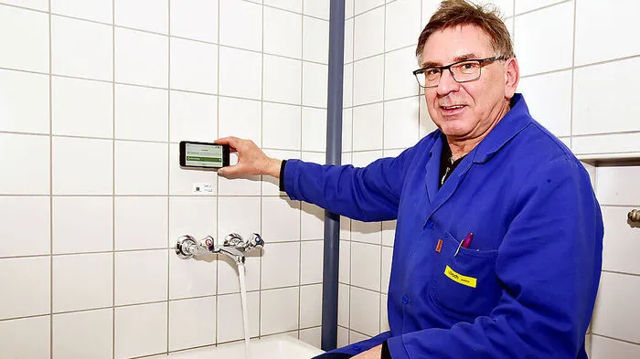 Schulwart Peter Warmuth spült in der Friedensschule mit Unterstützung von Smartphone und QR-Code