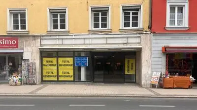 Eine Geschäftsfläche von außen, in den Auslagescheiben kleben mehrere Plakate, die auf einen Totalabverkauf hinweisen
