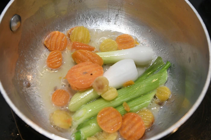 Jungzwiebel in wenig Butter mit Wasser weich dünsten, Karotten in Scheiben schneiden und dazugeben