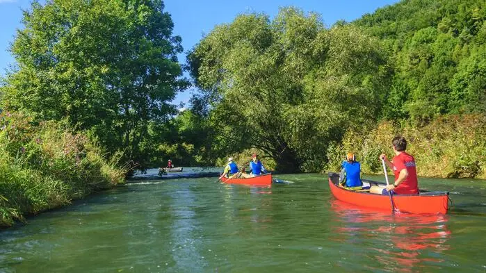 Kanufahrer sind auf einem grün umsäumten Fluss unterwegs