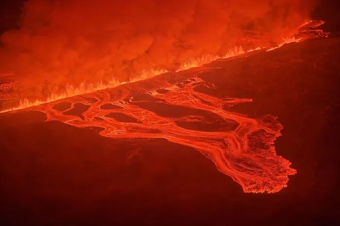 This handout picture released by the Icelandic Coast Guard on February 8, 2024 shows billowing smoke and flowing lava pouring out of a new fissure during a new volcanic eruption on the outskirts of the evacuated town of Grindavik, western Iceland. A volcanic eruption started on the Reykjanes peninsula in southwestern Iceland on Thursday, the third to hit the area since December, authorities said. (Photo by HANDOUT / Icelandic Coast Guard / AFP) / RESTRICTED TO EDITORIAL USE - MANDATORY CREDIT "AFP PHOTO /HANDOUT/ICELANDIC COAST GUARD " - NO MARKETING - NO ADVERTISING CAMPAIGNS - DISTRIBUTED AS A SERVICE TO CLIENTS