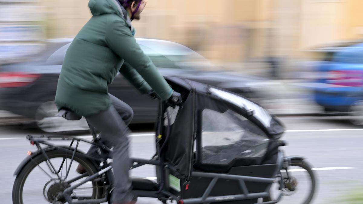 Im Bild: Eine Person fährt auf einem Lastenfahrrad | In den letzten drei Jahren sind an die zehntausend neue Lastenfahrräder auf Straßen Österreichs gekommen. Das Klimaministerium förderte seit 2020 rund 8.000 solcher Räder, mit denen sich Kinder, Haustiere oder auch Möbelstücke transportieren lassen, nun auch die Stadt Graz