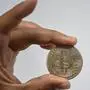 A man shows a souvenir coin depicting a bitcoin in Caracas on September 17, 2021. - According to a study by several universities, 96% of the population lives in poverty so video games that involve non-fungible tokens (NFTs) have unleashed a boom among the population that dreams with having a plant (Plant Vs Undead) that allows them to earn a bitcoin to get out of poverty. (Photo by Yuri CORTEZ / AFP)
