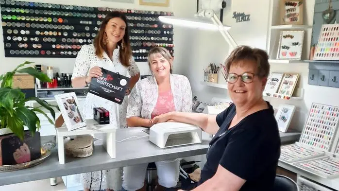 Drei Frauen an einem Tisch in einem Nagelstudio.