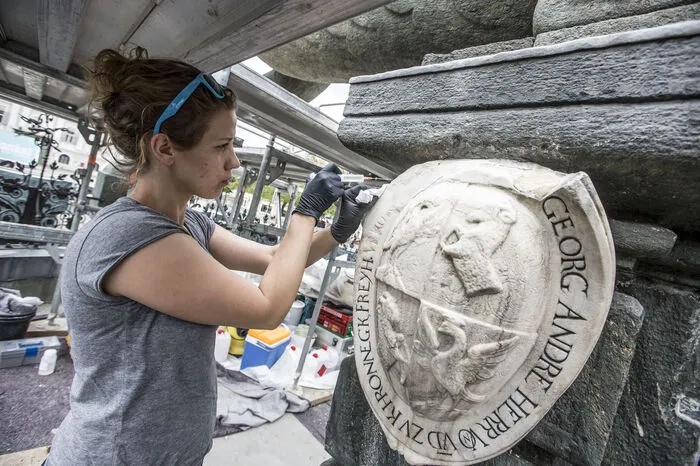 Barbara Rankl, eine der Restauratorinnen arbeitet mit einer "Spritze" am Klagenfurter Denkmal.