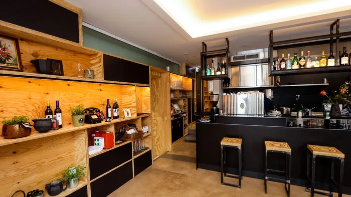 Ein Holzregal als Mini-Shop, auf dem auch Produkte befreundeter Produzenten und Künstlerinnen verkauft werden, eine große Bar ...