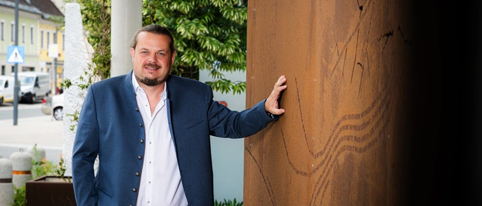Der Kandidat steht bei einer Holzwand