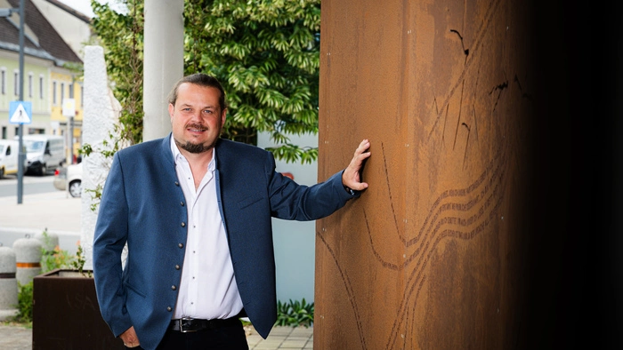 Der Kandidat steht bei einer Holzwand