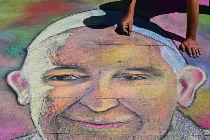 Der Straßenkünstler Andrea Starineri bei der Arbeit an einem Kreidekunstwerk, das den verstorbenen Papst Franziskus zeigt 