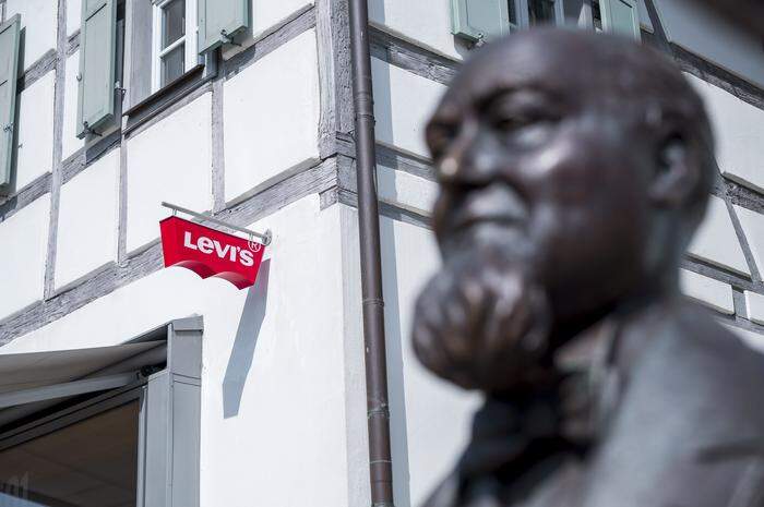 Buttenheim in Bayern: Das Levi·s Logo hängt an der Außenfassade des Levi Strauss Museums, davor ist der Kopf der Statue von Levi Strauss zu sehen 