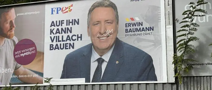 Ein Wahlplakat mit einem Mann im Anzug links neben ihm steht: „Auf ihn kann Villach bauen“