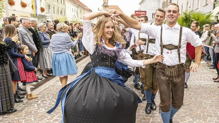 Ein junger Mann und eine junge Frau in trachtiger Kleidung tanzen.