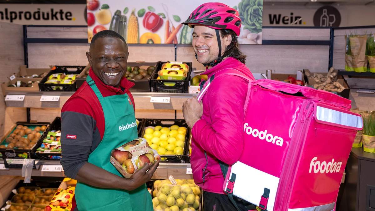 Ein Penny-Mitarbeiter und mit einem foodora-Mitarbeiter | Mit Nußdorf-Debant wird erstmals auch eine Gemeinde in Osttirol Teil des gemeinsamen Lieferservices von PENNY und foodora