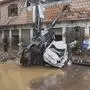 Local residents walk next to damaged cars stuck with an electric pole following flash flooding due to heavy rains at a neighbourhood of Mingora, the main town of Swat Valley, northwestern Pakistan, Friday, Aug. 15, 2025. (AP Photo/Naveed Ali)