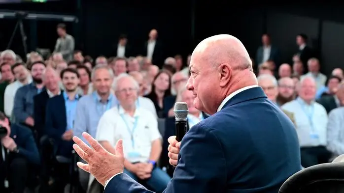 Christian Stocker sitzt mit einem Mikrofon in der Hand. Vor ihm sitzt ein Publikum.