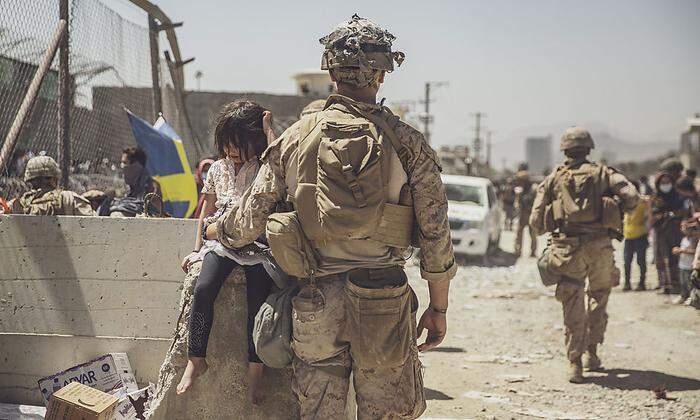 Ein US-Soldat kümmert sich um ein kleines Mädchen am Flughafen