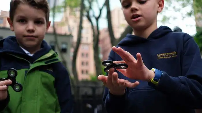 Tom Wuestenberg (8) und sein zehnjähriger Bruder Louis spielen mit dem Fidget Spinner in einem Park in New York.