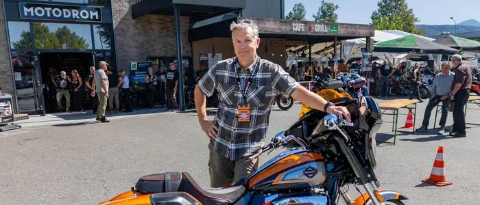 Ein Mann in Karohemd lehnt sich an eine Harley Davidson