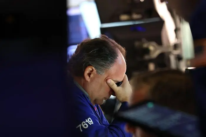 A trader works at his desk on the floor of the New York Stock Exchange (NYSE) in New York on October 7, 2025. Wall Street stocks edged higher early Tuesday, extending an upbeat stretch as markets continue to look past a US government shutdown that has curtailed economic data releases. (Photo by TIMOTHY A. CLARY / AFP)