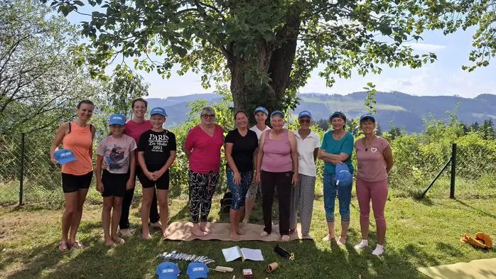 Mehrere Personen unterschiedlichen Alters stehen in sommerlicher Kleidung vor einem Baum