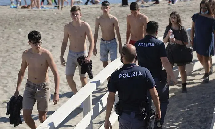Police officer carry out anti-gathering checks on the beach in Ostia, near Rome, Saturday, May 23, 2020. Since Monday, Italians have regained freedoms, including being able to sit down at a cafe or restaurant, shop in all retail stores or attend church services such as Mass after a partial lifting of restriction measures aimed at containing the spread of COVID-19. (Mauro Scobogna/LaPresse via AP)