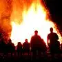 Menschen stehen um ein großes Osterfeuer
