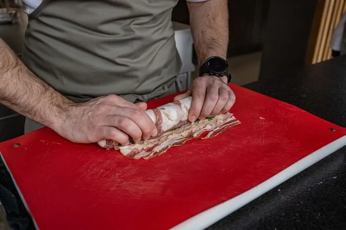 Wenn es halb eingeschlagen ist, werden die überlappenden Enden des Specks eingeklappt und dann wird weiter eingerollt, bis das Filet komplett eingewickelt ist.