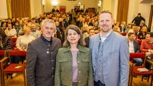Zwei Männer und eine Frau, hinter ihnen ein mit Zuhörern voll besetzter Saal | Die Bürgermeisterkandidaten Claus Faller (LJJ), Sylvia Petschar (SPÖ) und Markus Schiffer (ÖVP)